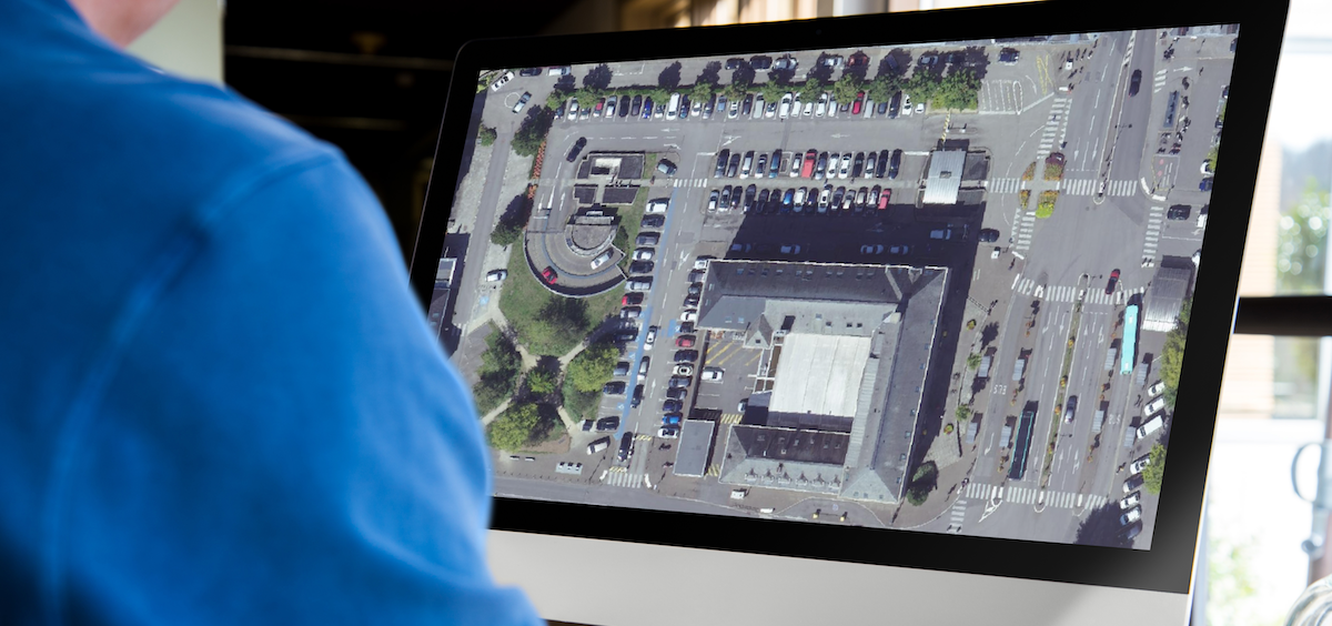Homme travaillant sur un ordinateur de type iMac et affichant un système d'information géographique